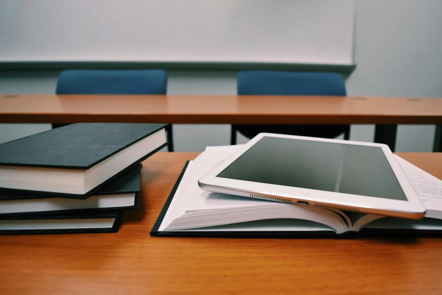 Bücher und Laptop auf dem Holztisch von HK-Pädagogik